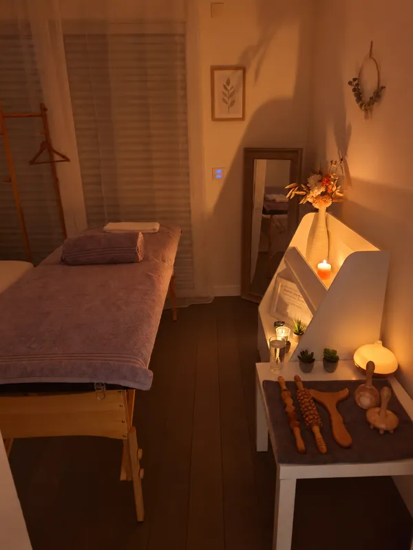 Les instruments de madérothérapie en bois disposés sur la console de la salle de soin, à côté de la table de massage, à la lueur d'une bougie